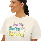 Woman wearing a white t-shirt with colorful text 'Smile You're in Sea Isle'